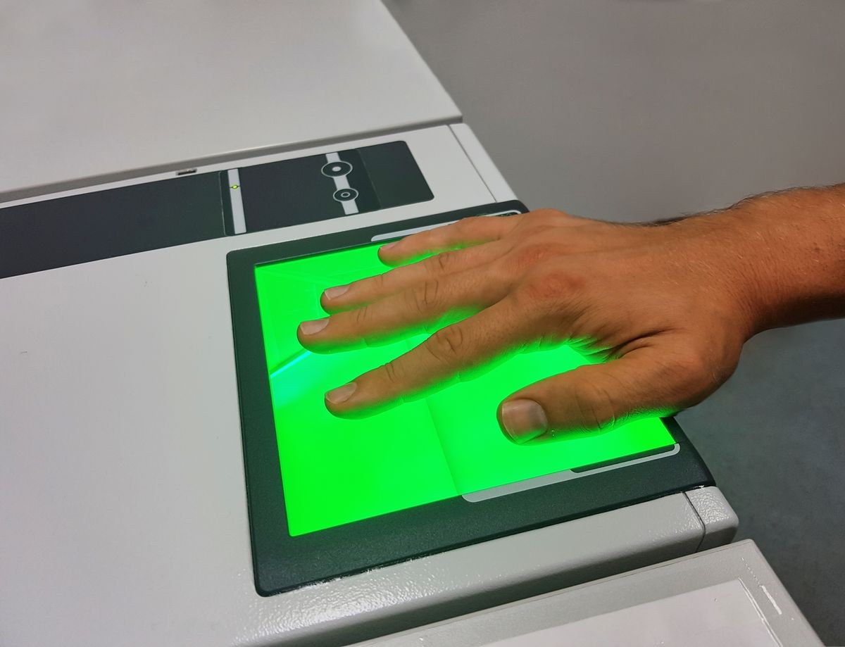 A man uses a fingerprint scanner for identification. Biometrics or cybersecurity concepts.